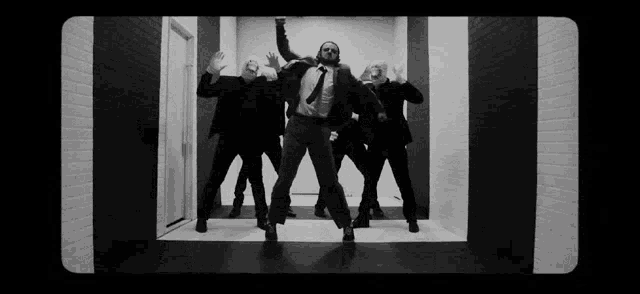 a group of men in suits and ties are dancing in a room