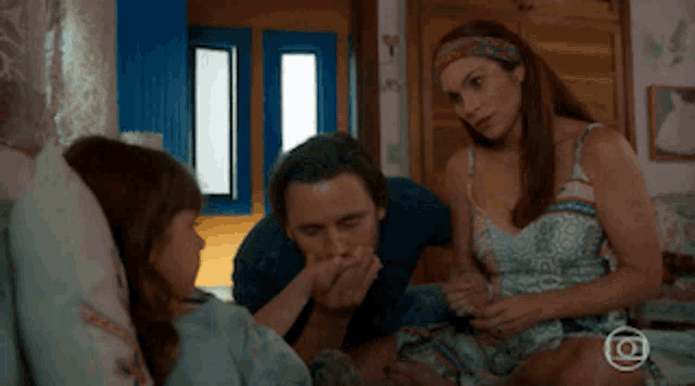 a man and a woman are talking to a little girl in a bedroom
