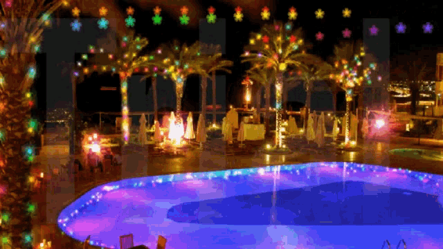 a swimming pool is lit up at night with christmas lights