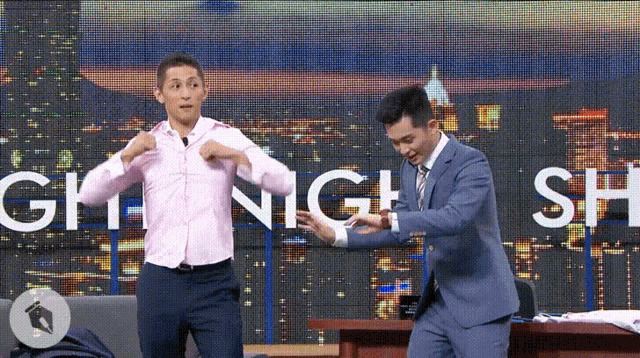 a man in a suit and a man in a pink shirt are standing in front of a sign that says gh night show