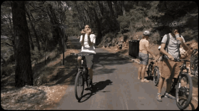 a man wearing a helmet is riding a bike on a road with other people