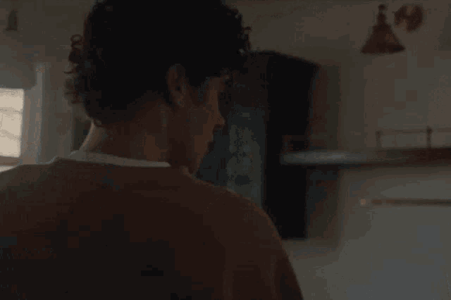 a man is standing in a kitchen holding a box .