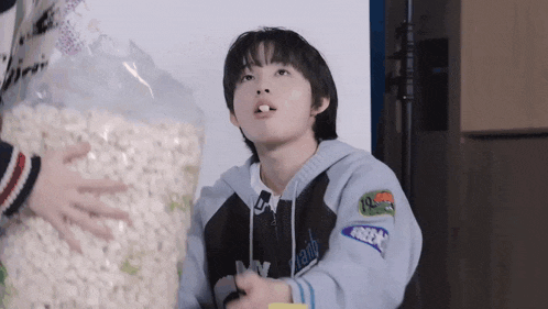 a young boy is eating a bag of popcorn while holding a video game controller .