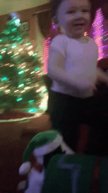 a baby is sitting in front of a christmas tree wearing a santa hat
