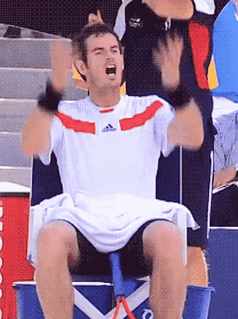 a man wearing an adidas shirt sits on a chair