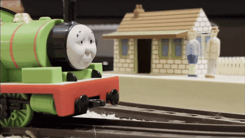 a green toy train with a sad face on it