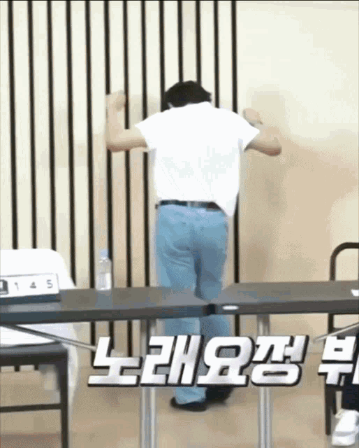 a man in a white shirt and blue jeans is standing in front of a table with the number 145 on it
