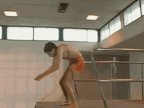 a man is standing on a diving board in a pool .