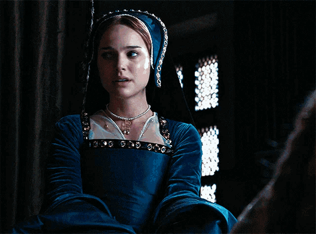 a woman in a blue dress with a pearl necklace and a hood
