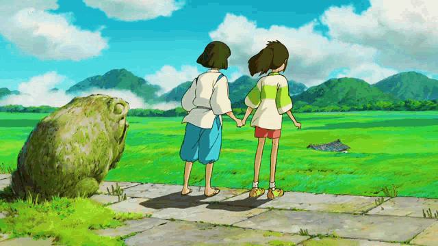 a couple of people standing on a sidewalk holding hands in a field