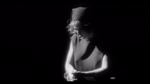 a black and white photo of a woman praying in the dark
