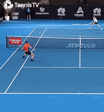 two tennis players are playing on a tennis court with an emirates fit better banner on the net