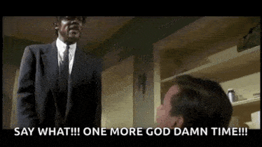 a man in a suit and tie is talking to another man in a room .