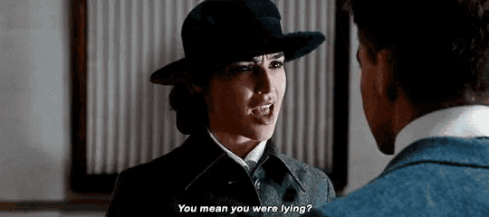 a woman in a hat is talking to a man in a suit and says " you mean you were lying ? "