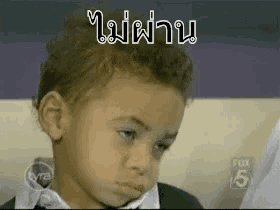 a young boy is sitting in a chair with a foreign language written on his face .