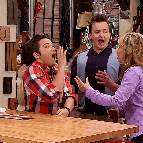 a man in a plaid shirt is making a funny face while a woman in a purple shirt stands behind him