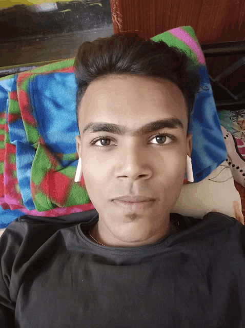 a man laying on a bed with a colorful blanket