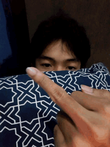 a person laying on a bed with a blue and white patterned blanket