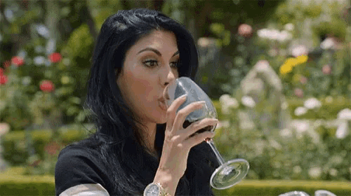 a woman is drinking a glass of wine .