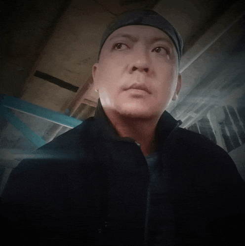 a man wearing a headband and a black jacket is looking up