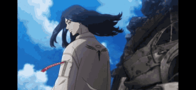 a man with long black hair is standing in front of a building with a blue sky in the background .