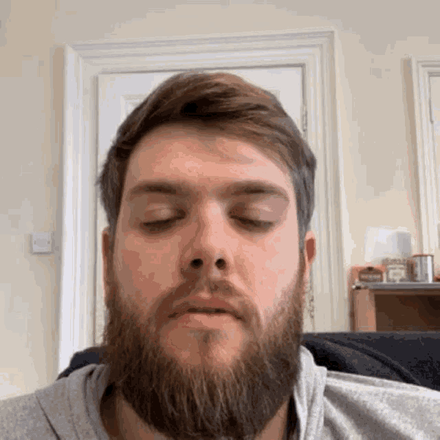 a man with a beard is sitting on a chair with his eyes closed