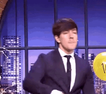a man in a suit and tie is standing in front of a yellow balloon .