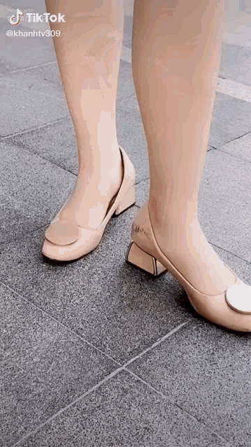 a woman is wearing a pair of beige shoes on a tile floor .
