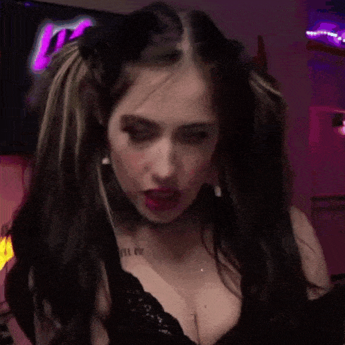 a woman with pigtails and a choker is making a funny face in a room .