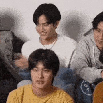 a group of young men are sitting next to each other on a couch .