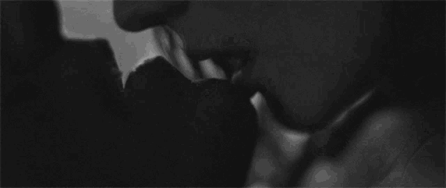 a black and white photo of a man and woman kissing each other .