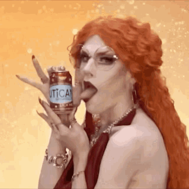 a drag queen is sticking her tongue out while holding a can of utica .