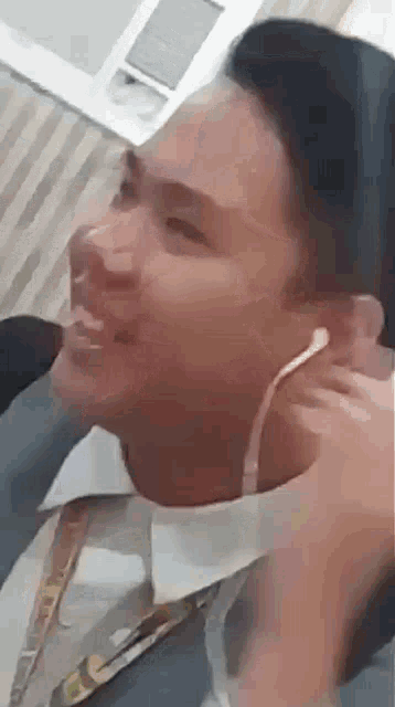 a man wearing ear buds is smiling while sitting down .