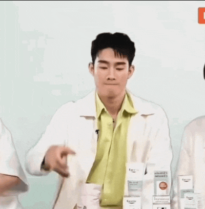 a man in a white coat is holding a piece of paper and making a face .
