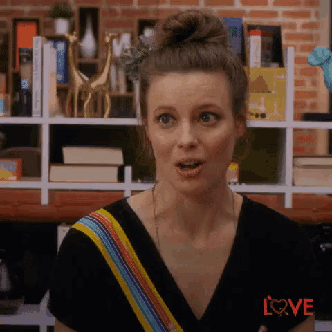 a woman with a bun on her head is standing in front of a bookshelf with books on it .