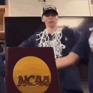 a man is holding a ncaa trophy in front of him .