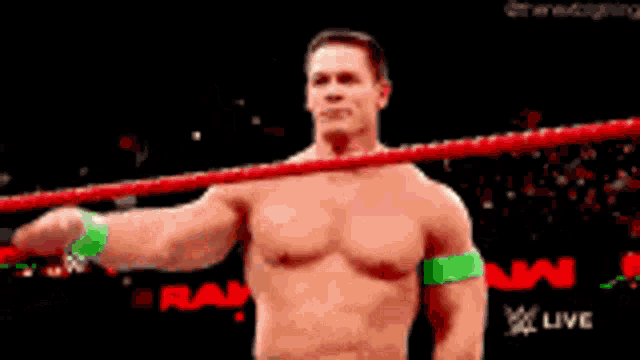 a shirtless wrestler salutes while standing in a wrestling ring .
