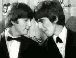 two men in tuxedos and bow ties are standing next to each other and looking at each other .