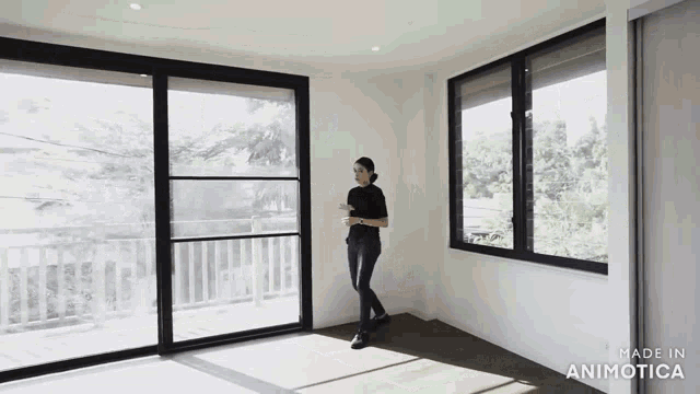 a woman is standing in an empty room with a lot of windows and a balcony .
