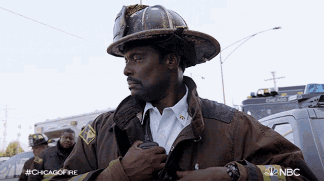 a man in a fireman 's uniform is holding a walkie talkie in his hand