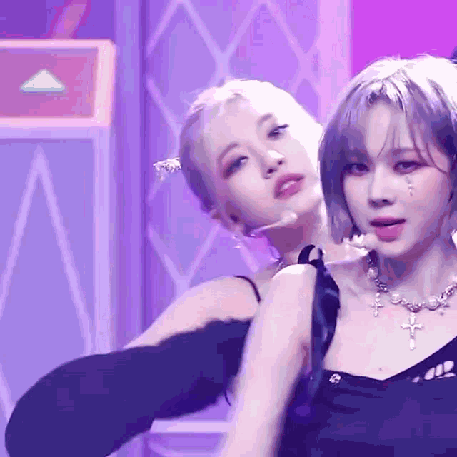 two women are dancing on a stage and one has a cross necklace