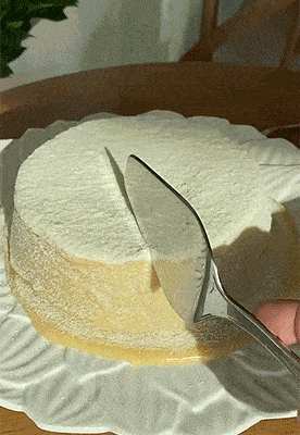 a person is cutting a cake with a spatula on a white plate