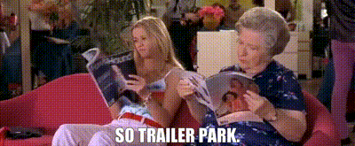 two women are sitting on a couch reading magazines and the caption reads `` so trailer park '' .