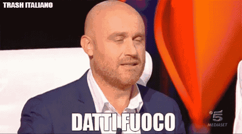 a bald man with a beard is standing in front of a red hot air balloon and says " batti fuoco "
