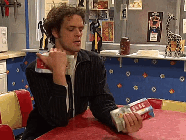 a man is sitting at a table holding a package of rice