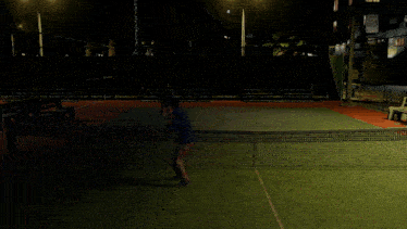 a man playing tennis at night with a sign that says no parking