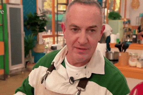 a man wearing a green and white striped shirt and an apron is standing in a kitchen