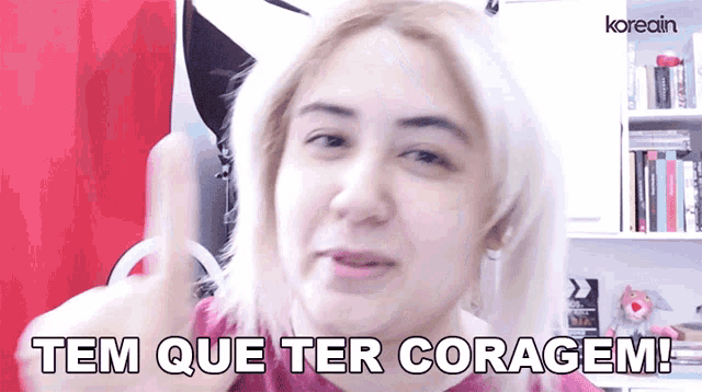 a woman says tem que ter coragem in front of a bookshelf