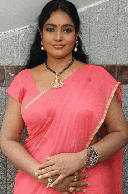a woman wearing a pink top and a necklace with pearls