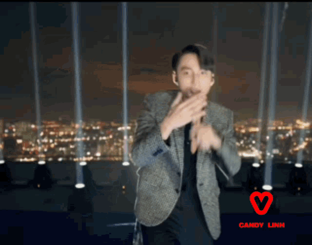 a man in a suit is dancing in front of a city skyline with candy link written on the bottom right